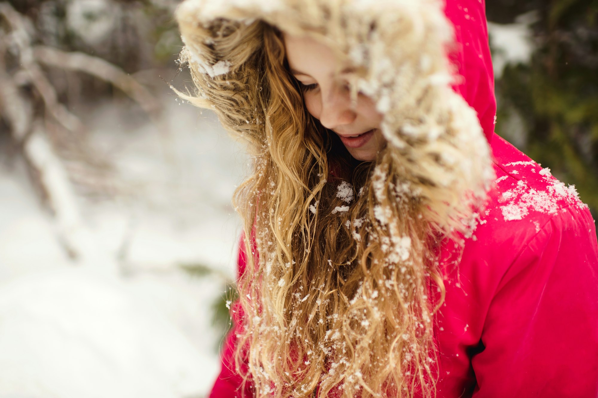 Girl in parka with snow in her hair looking down